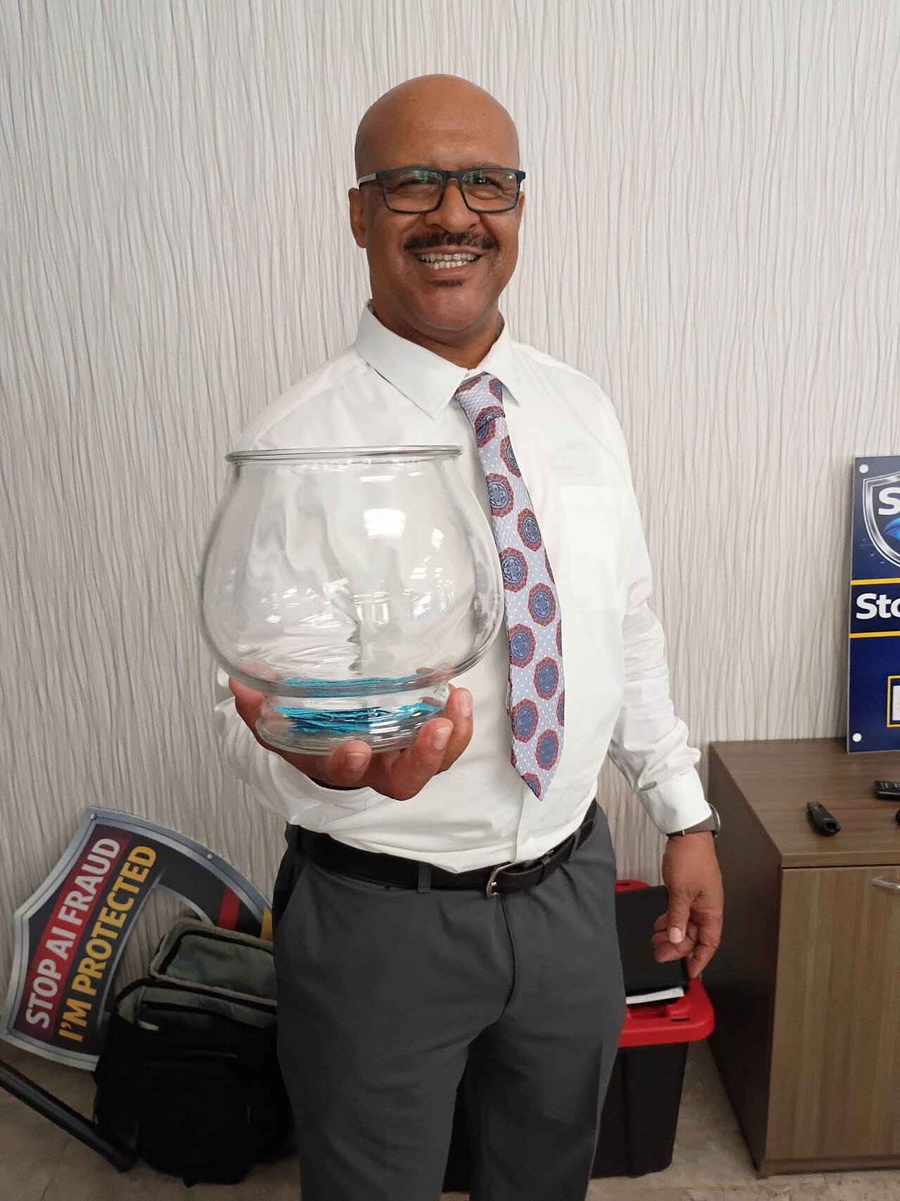 StopAiFraud founder Gary Williams holds a glass raffle bowl of tickets during the AI fraud awareness event at Lifespan Walk Café in Rochester.